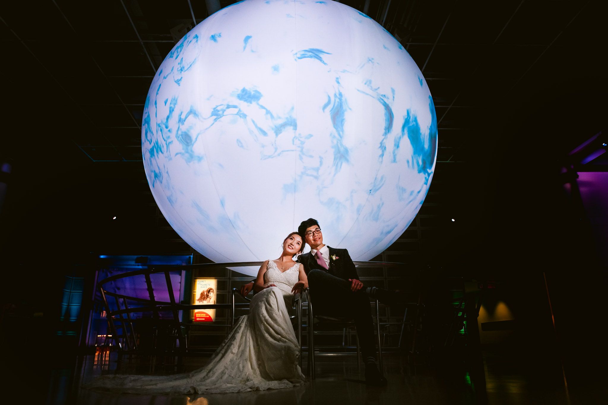 Wedding venue illuminated with large glowing white balloon-like spherical lights in dark setting.