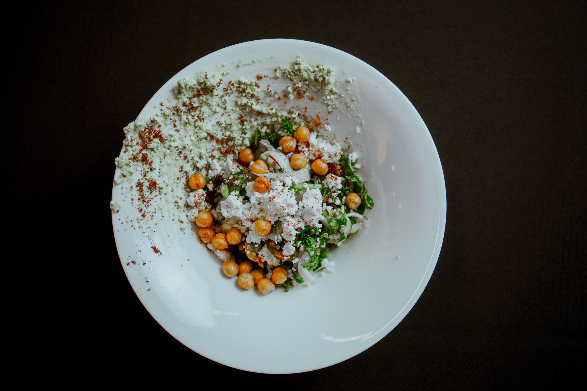 White plate with colorful garnished food presentation on dark background.