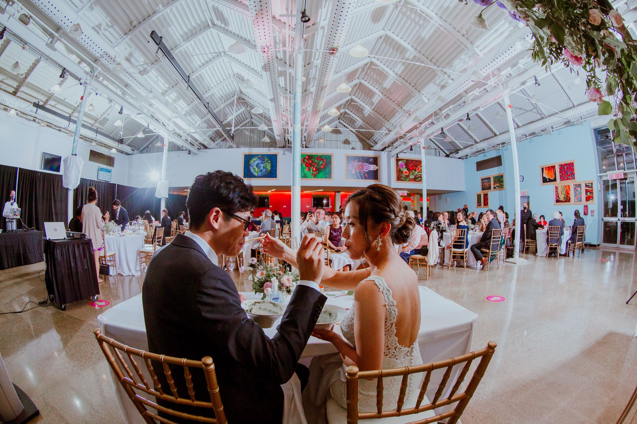 Wedding reception venue decorated with white drapes and string lights creating an elegant atmosphere for dining.