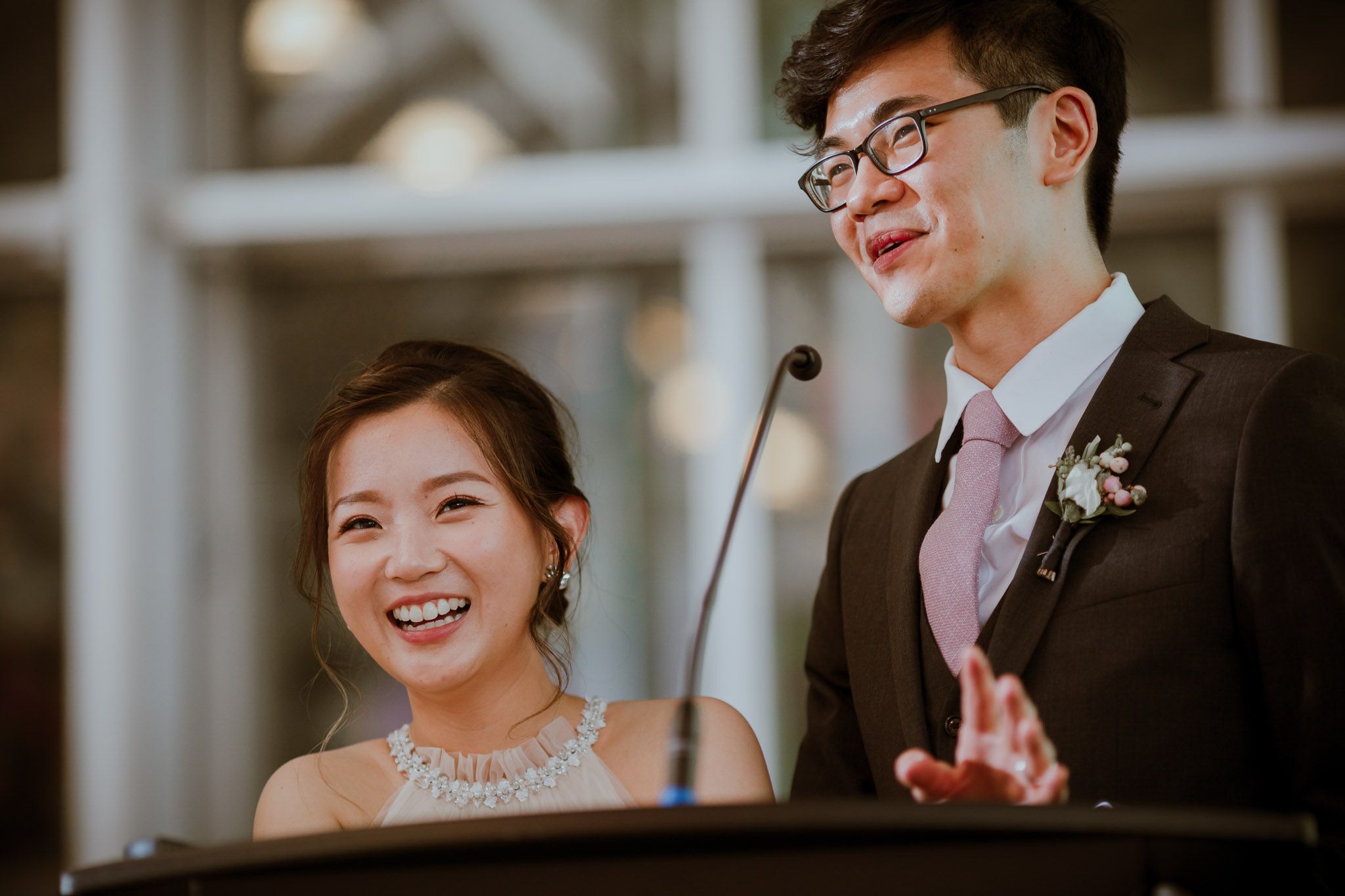 A couple shares a joyful moment while giving a speech at their wedding reception.