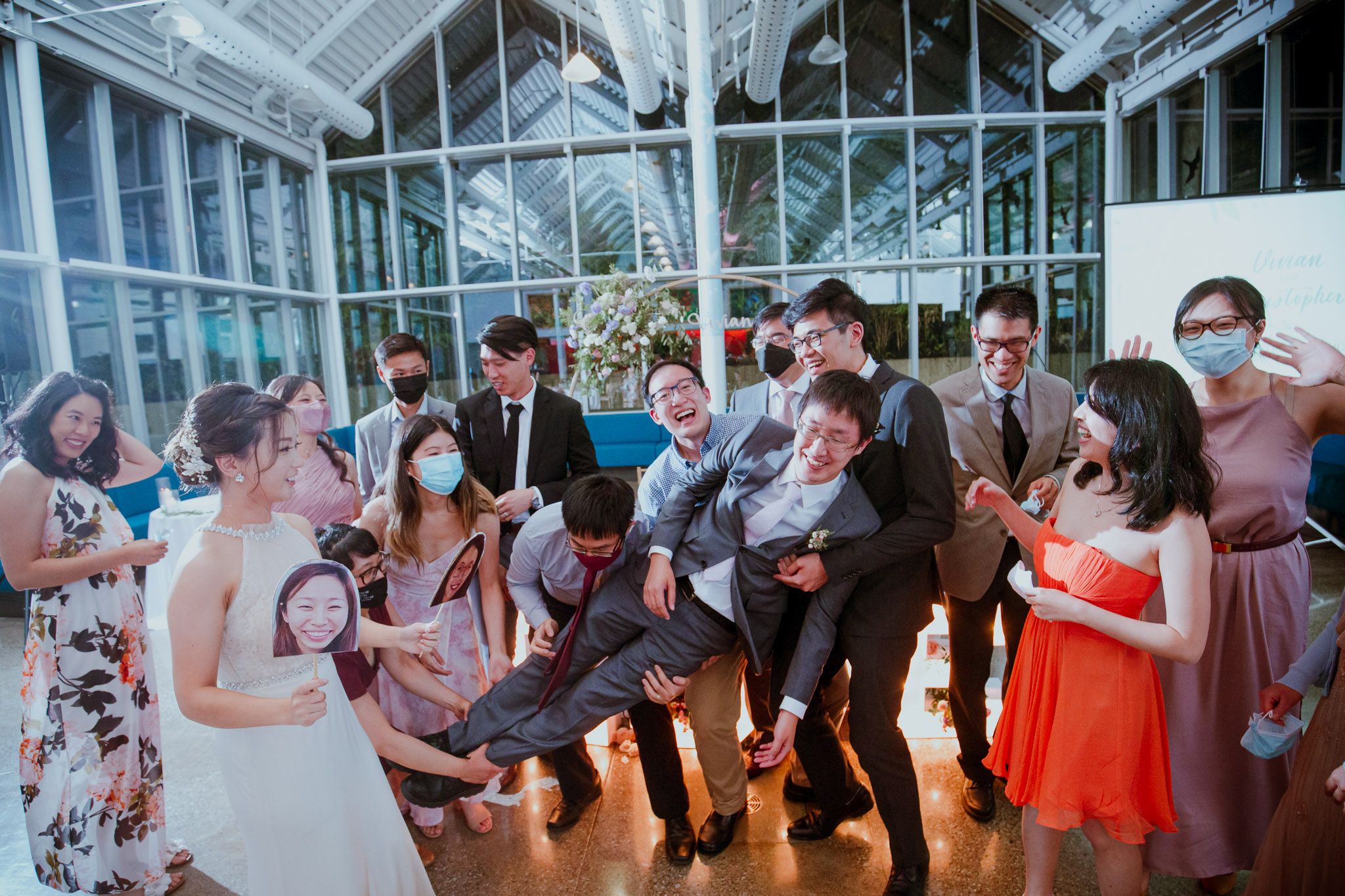 Wedding guests dancing together on a white dance floor at an indoor reception celebration.