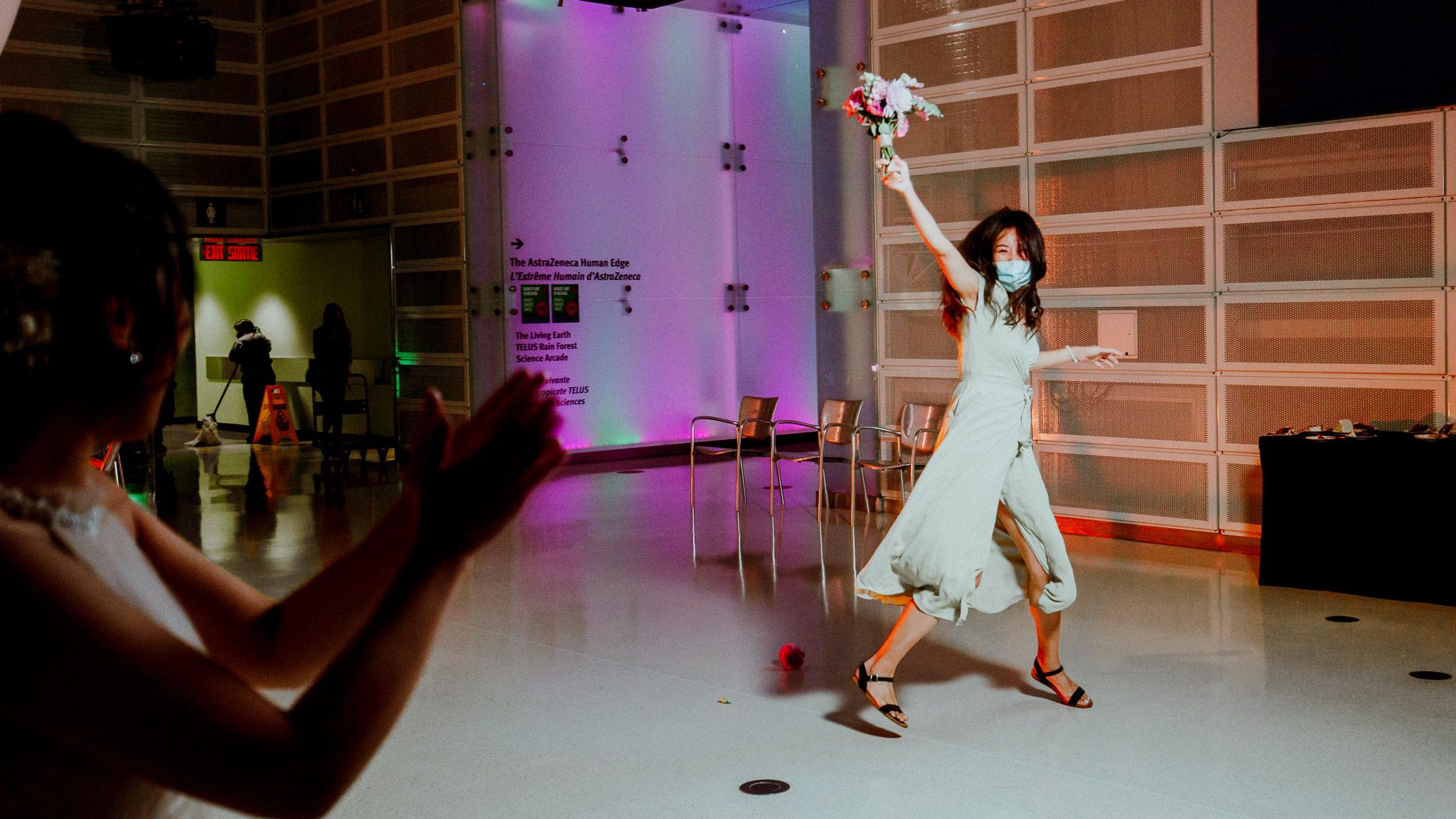 Couples dance together on a purple-lit dance floor during a wedding reception celebration.