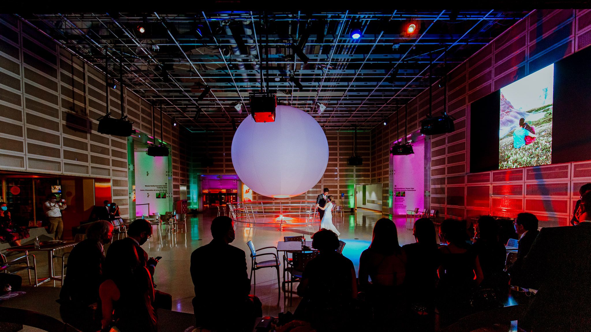 Dark event space illuminated with dramatic red and blue lighting creating an atmospheric ambiance.