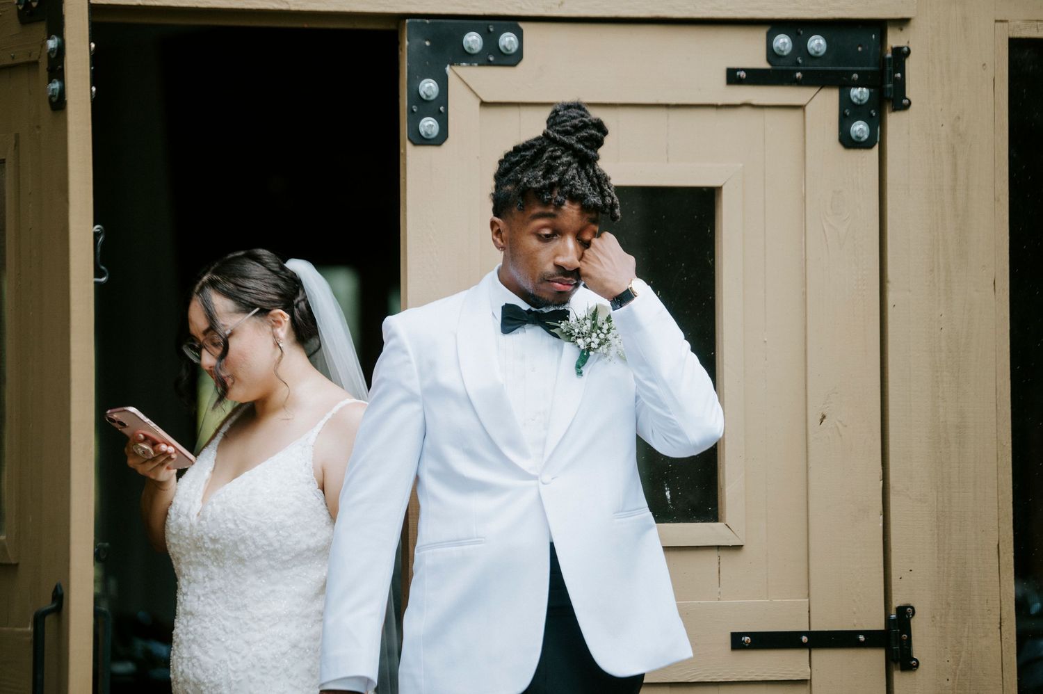 A couple in wedding attire shares a romantic moment against a rustic wooden wall backdrop.