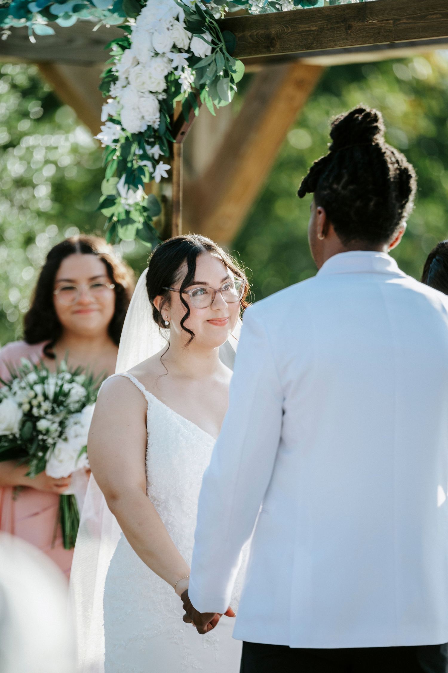 A bride and groom share an intimate moment during their outdoor garden wedding ceremony under green foliage.