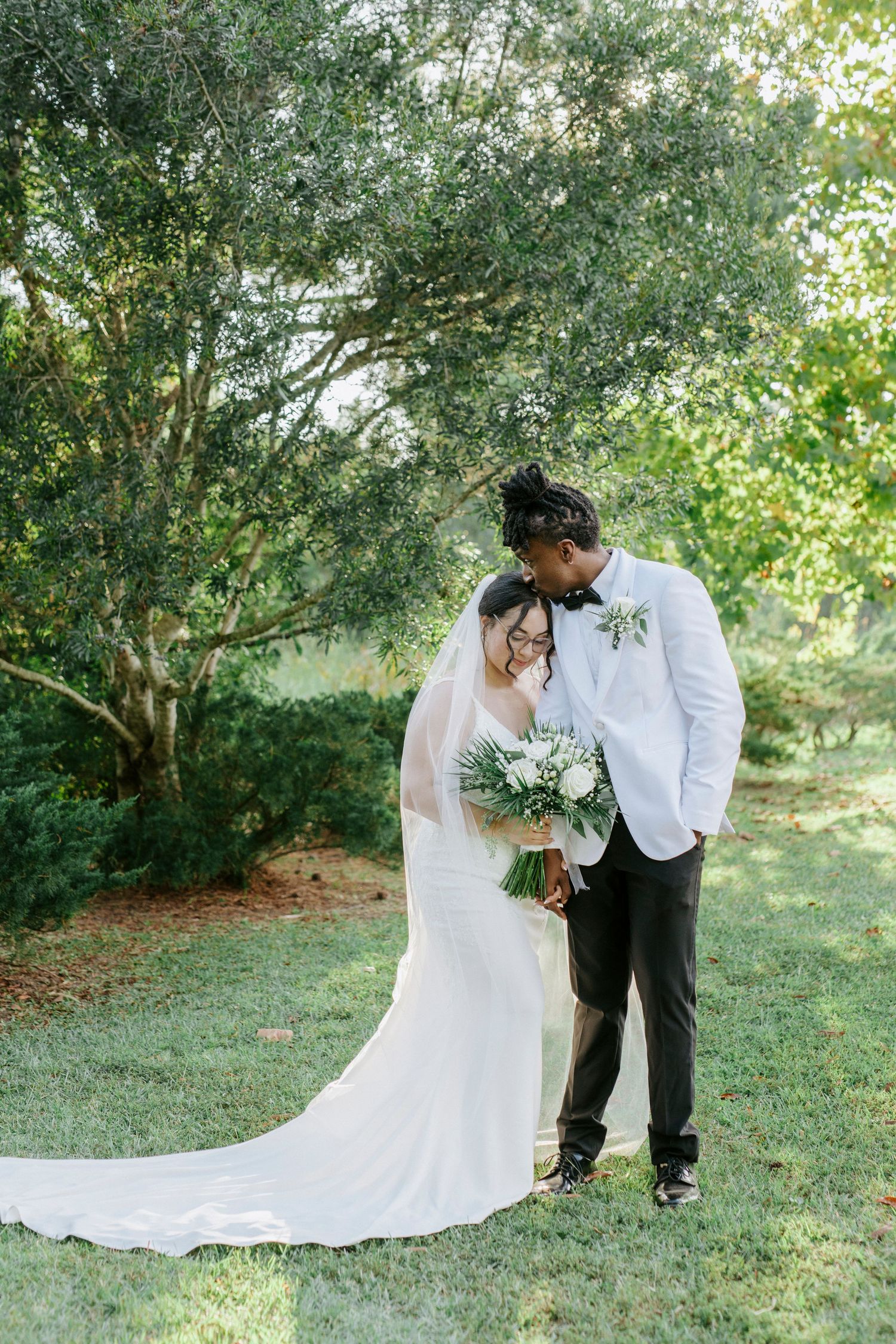 A romantic wedding photo series showing a couple in white attire posing together in a lush garden setting.