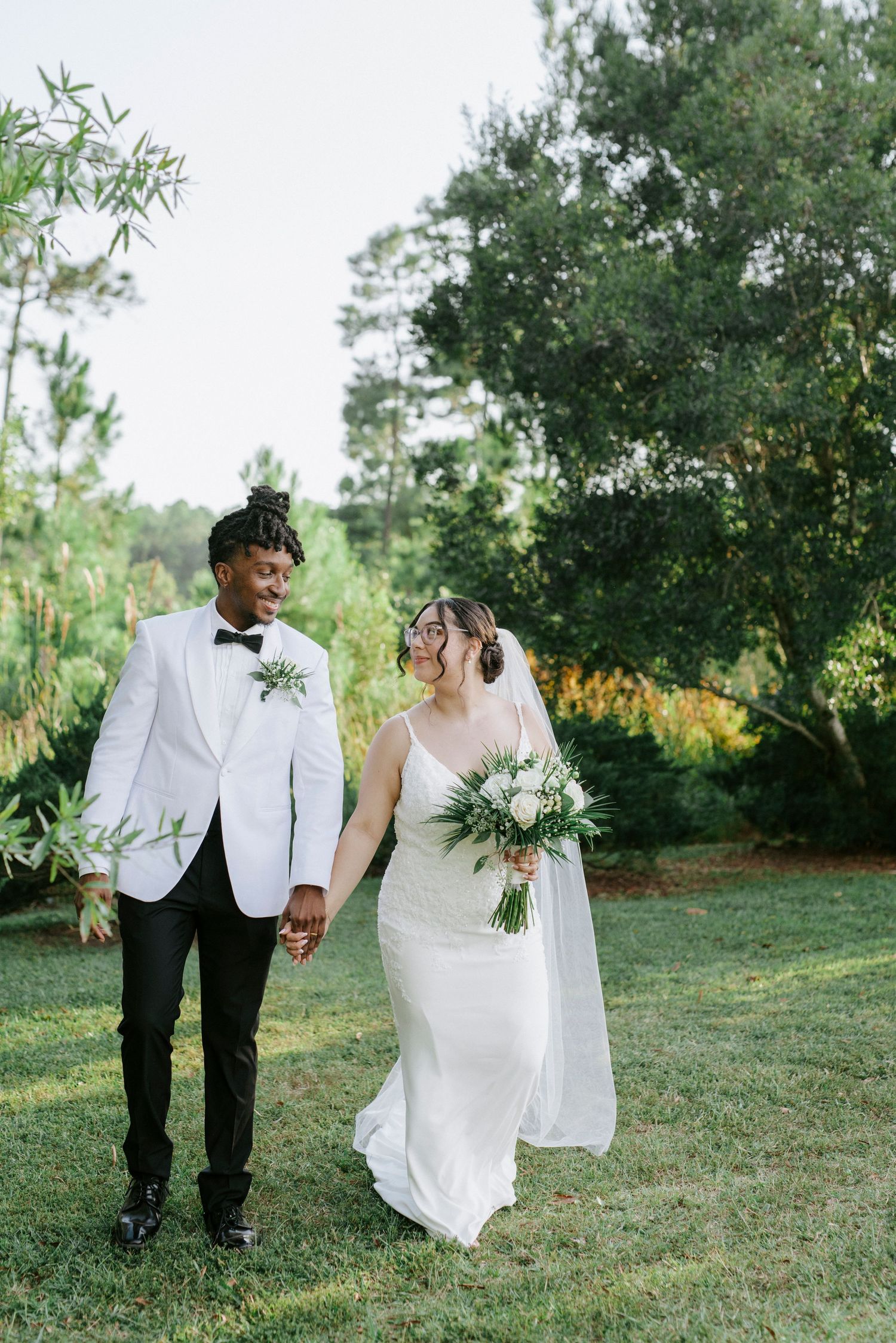 Candid wedding photos of a couple walking and posing together in a sunlit outdoor garden setting.