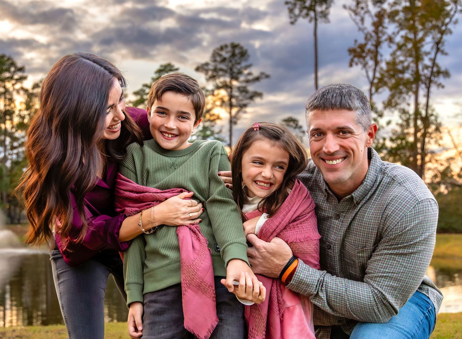 People laughing and hugging while posing together in casual attire during golden hour outdoors.
