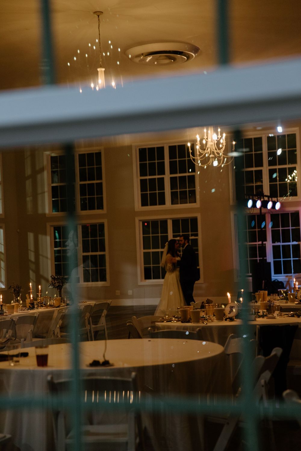 A dimly lit reception hall with twinkling lights and elegant table settings.