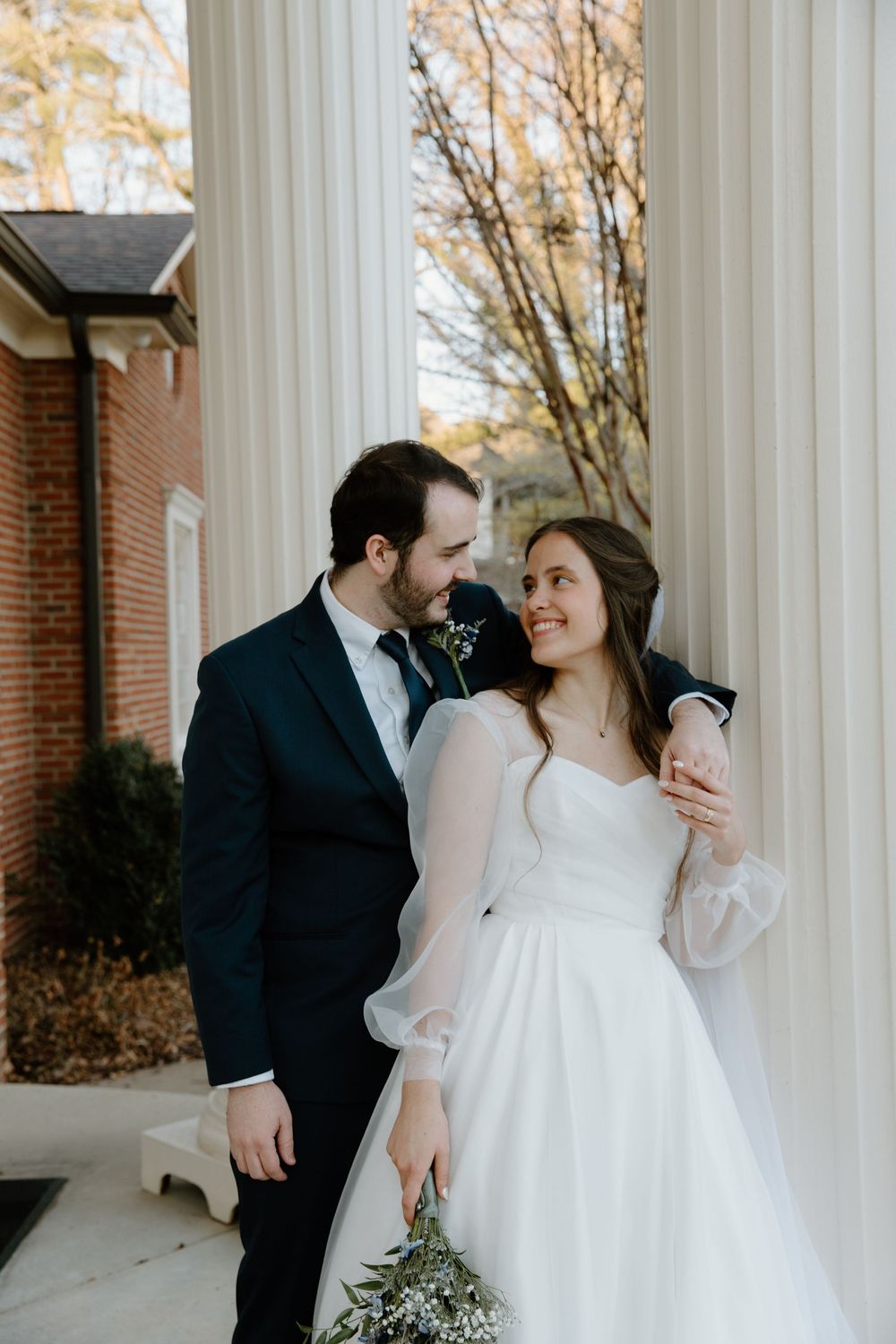 Wedding couple shares romantic moments between classic white columns.