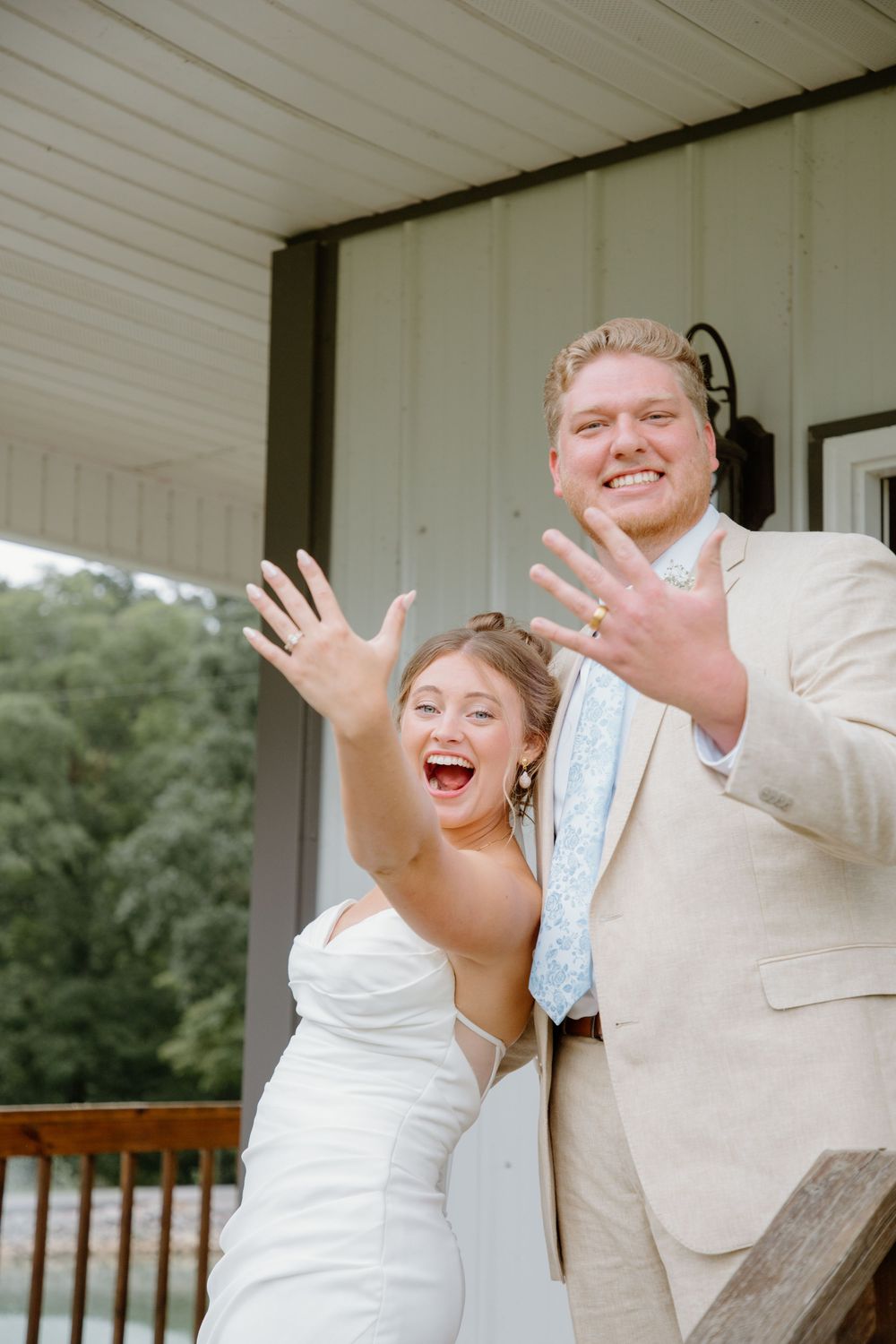 Joyful wedding couple celebrating with expressive gestures on a white porch.