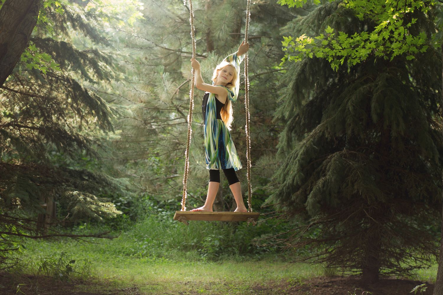 Creative Sioux Falls, SD photographer constructs swing in backyard for photo shoot with a child circus arts aerial artist performer.