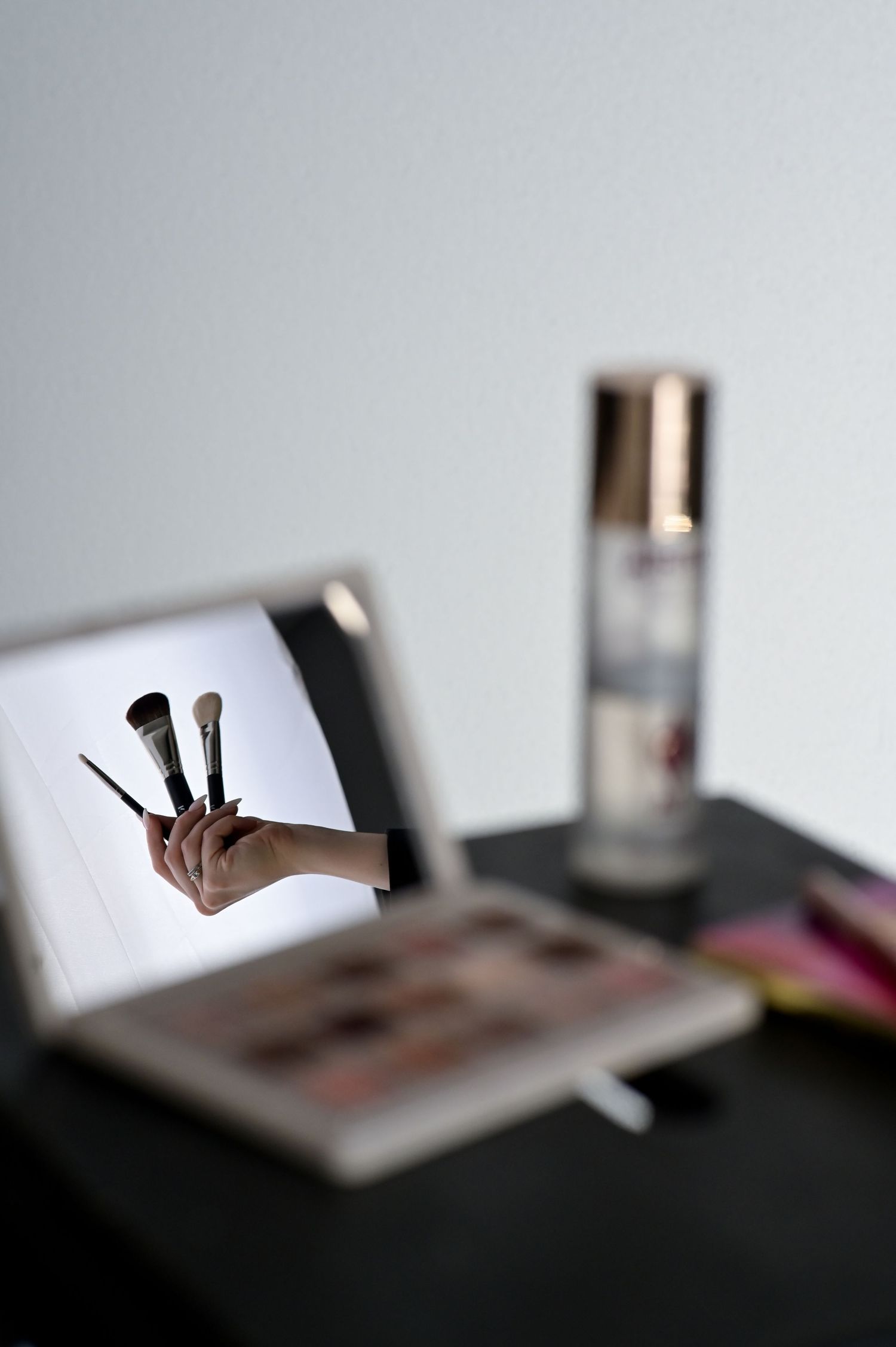 A sequence of blurred photos showing makeup brushes and cosmetic products arranged on a dark surface.