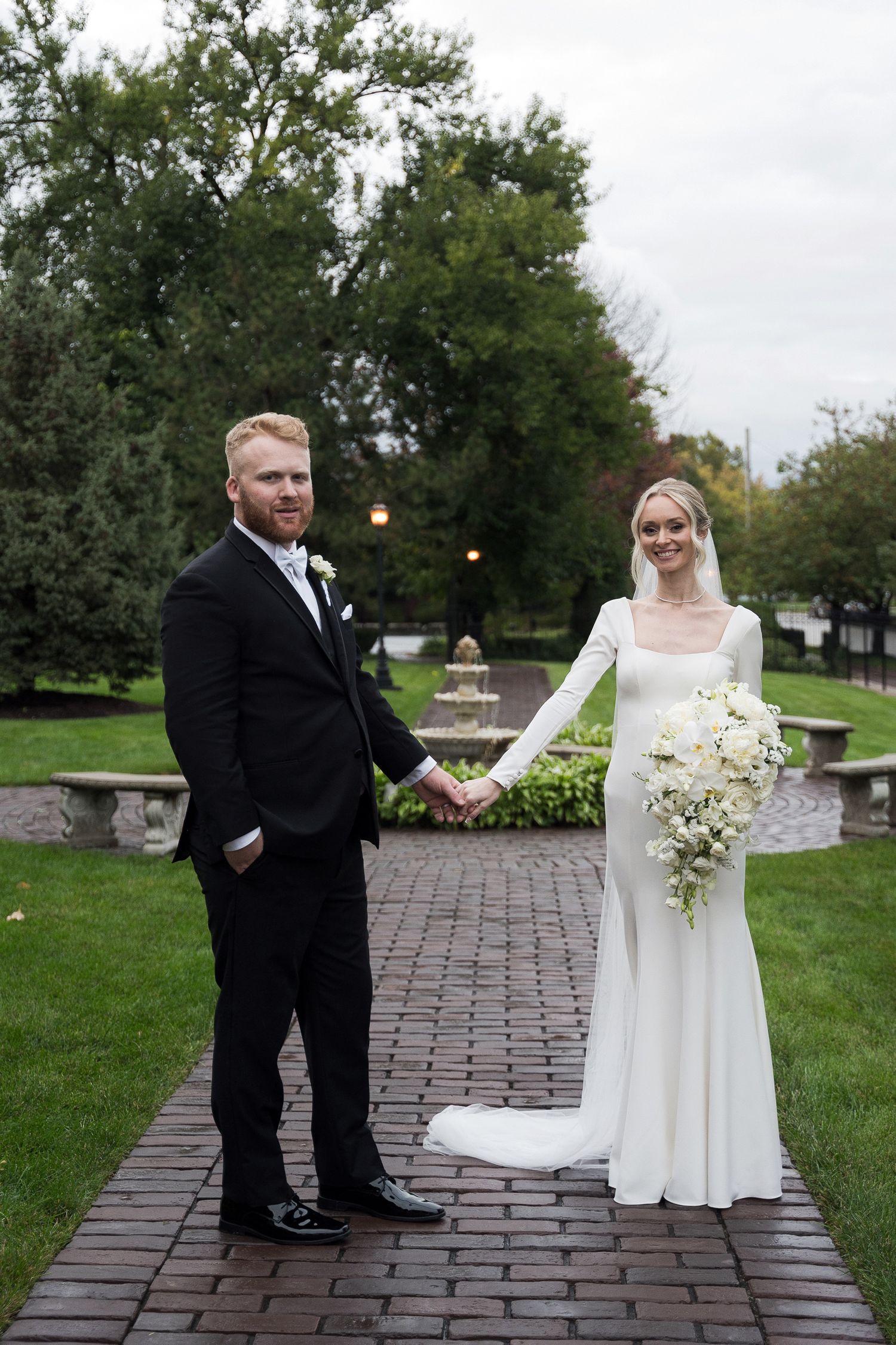 A couple shares a romantic moment on a brick pathway during their wedding day celebration.