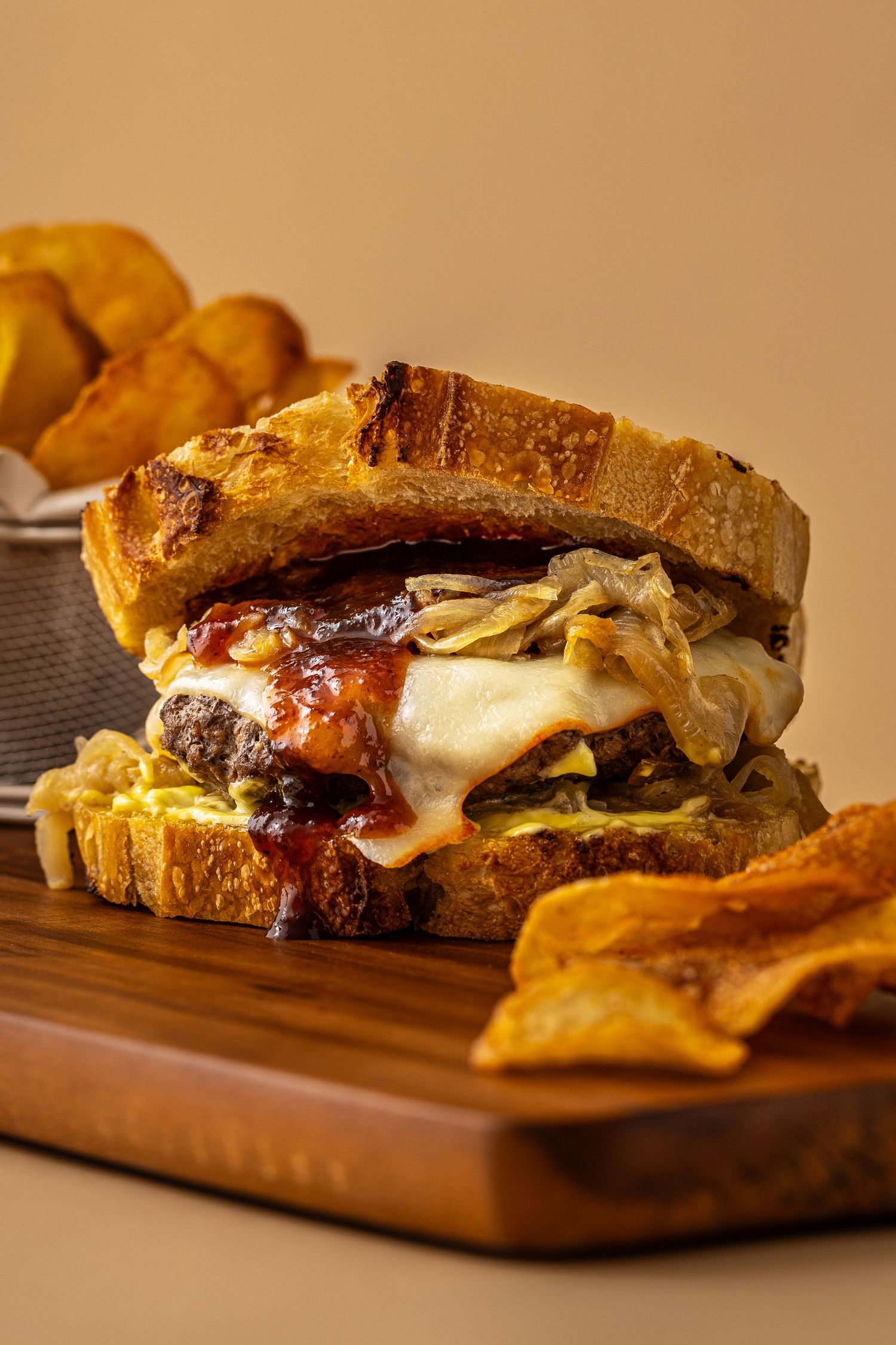 Hero shot of a scratch made cheeseburger on homemade sourdough bread with a side of chips made by Heartbakn in New Braunfels Texas