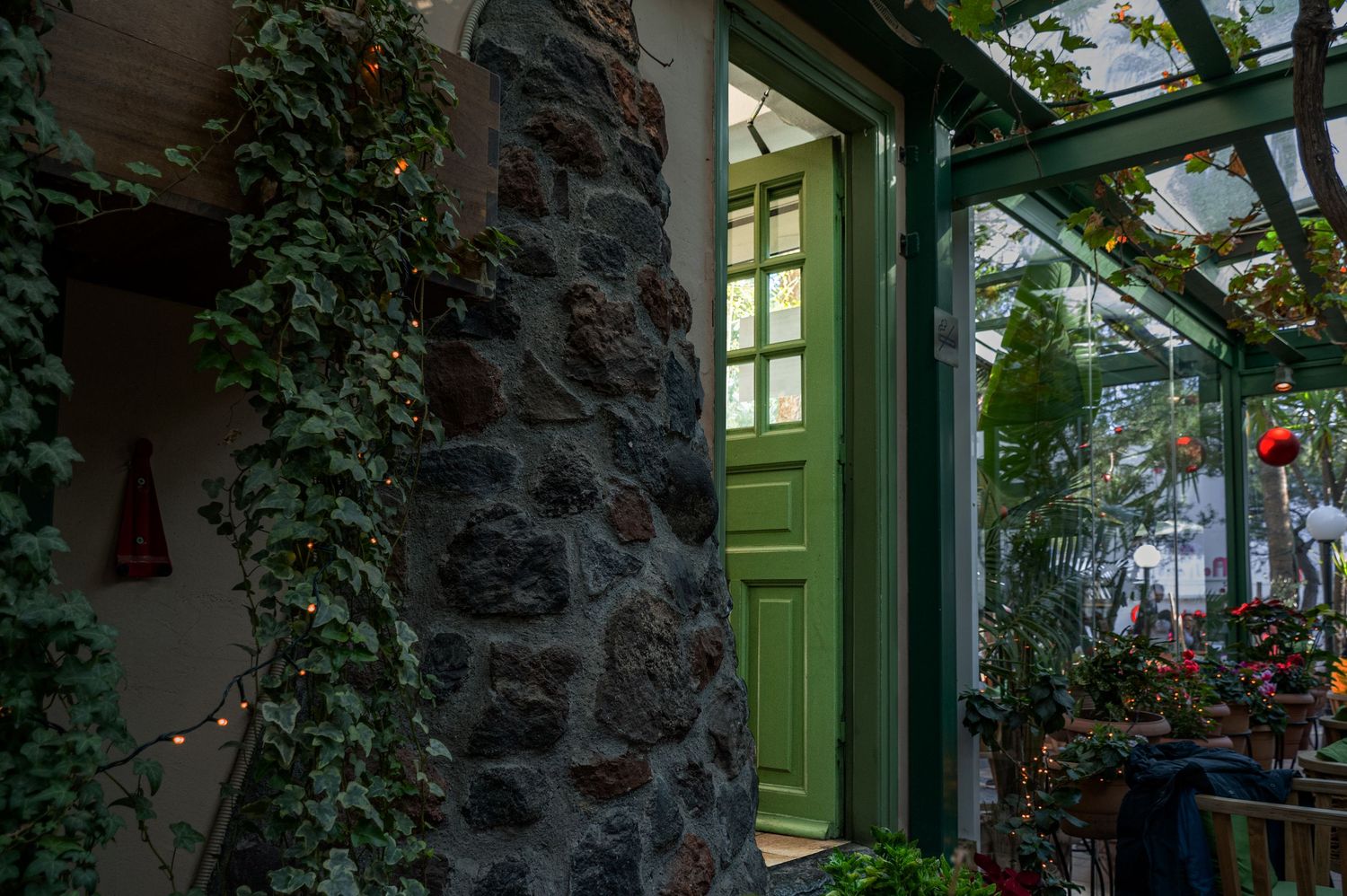 A charming stone wall with climbing ivy and green-framed windows creates a cozy cottage atmosphere.