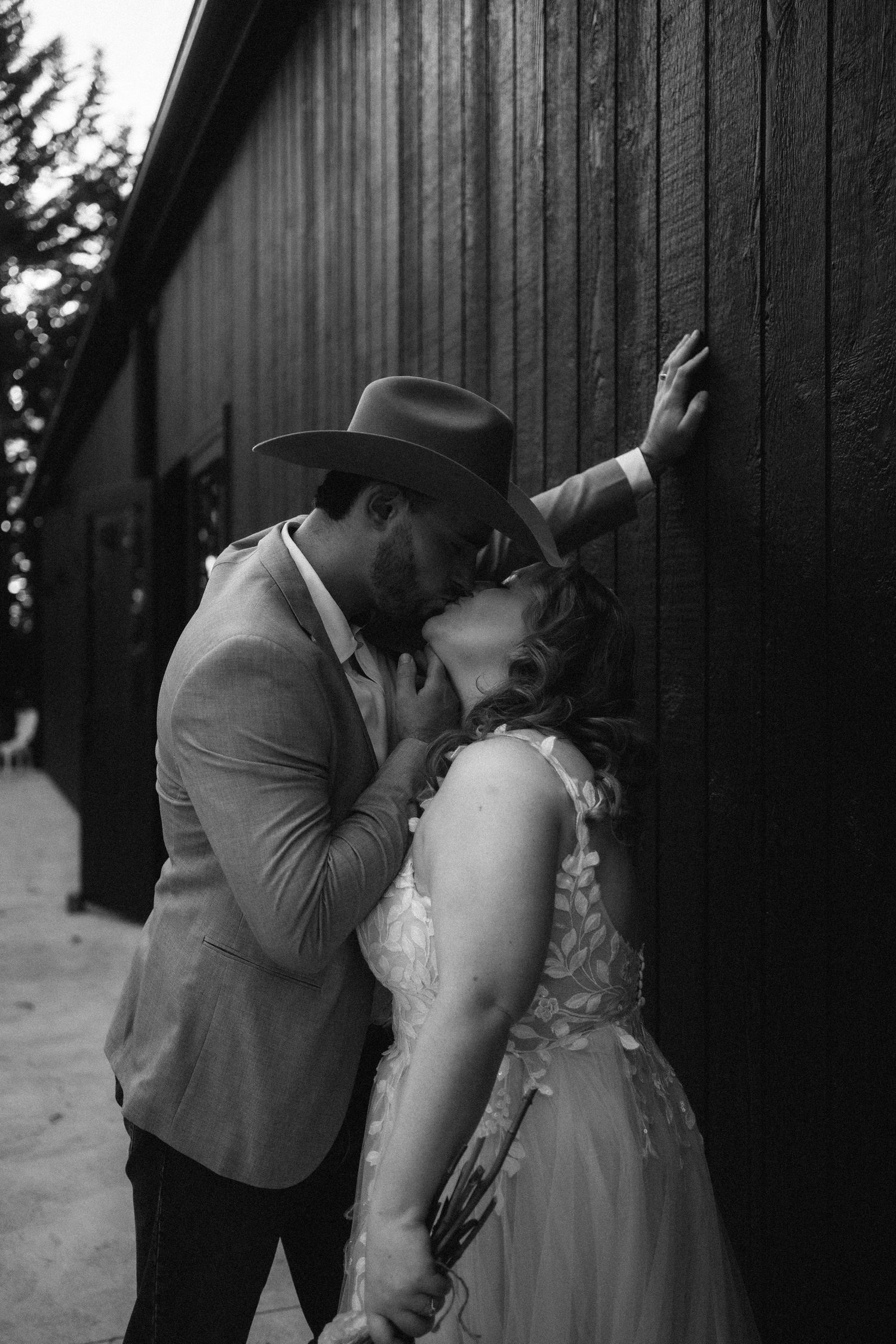 A romantic black and white wedding photo sequence shows a couple sharing an intimate kiss against a rustic barn wall.