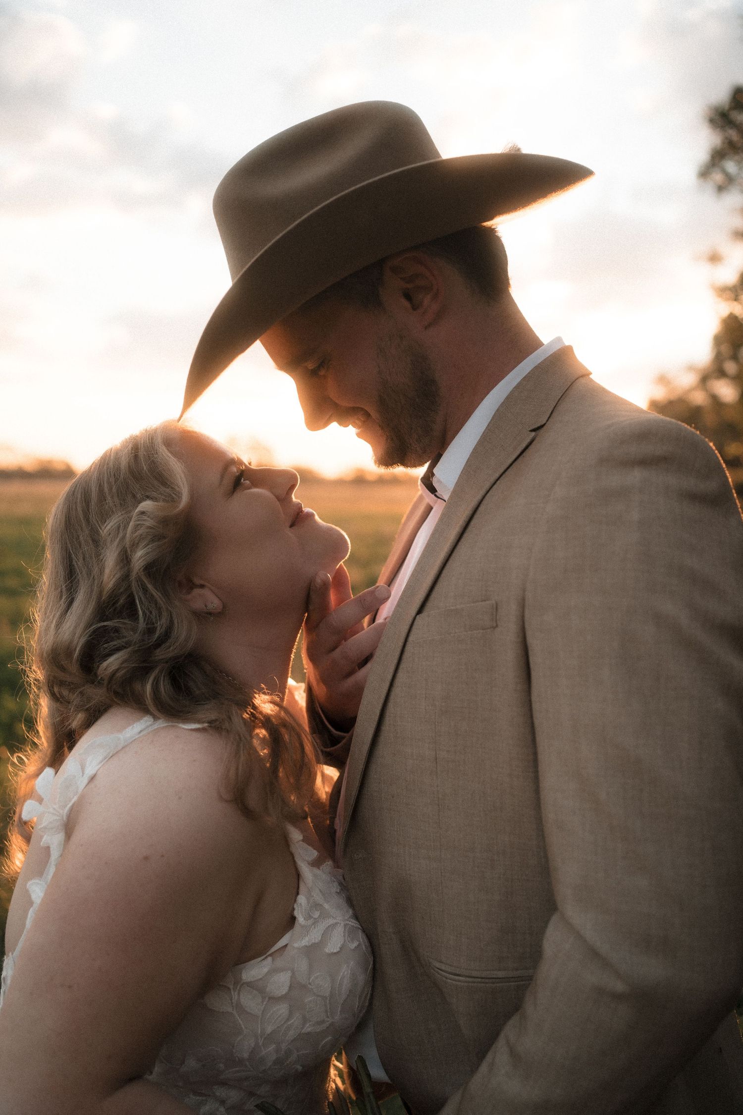 Romantic sunset silhouettes of couple in western attire sharing tender moments during golden hour photo session.