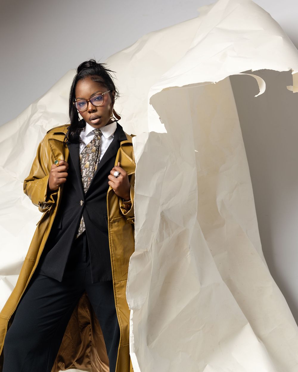 A series of fashion portraits showing someone in a mustard leather jacket and black outfit against a white backdrop.