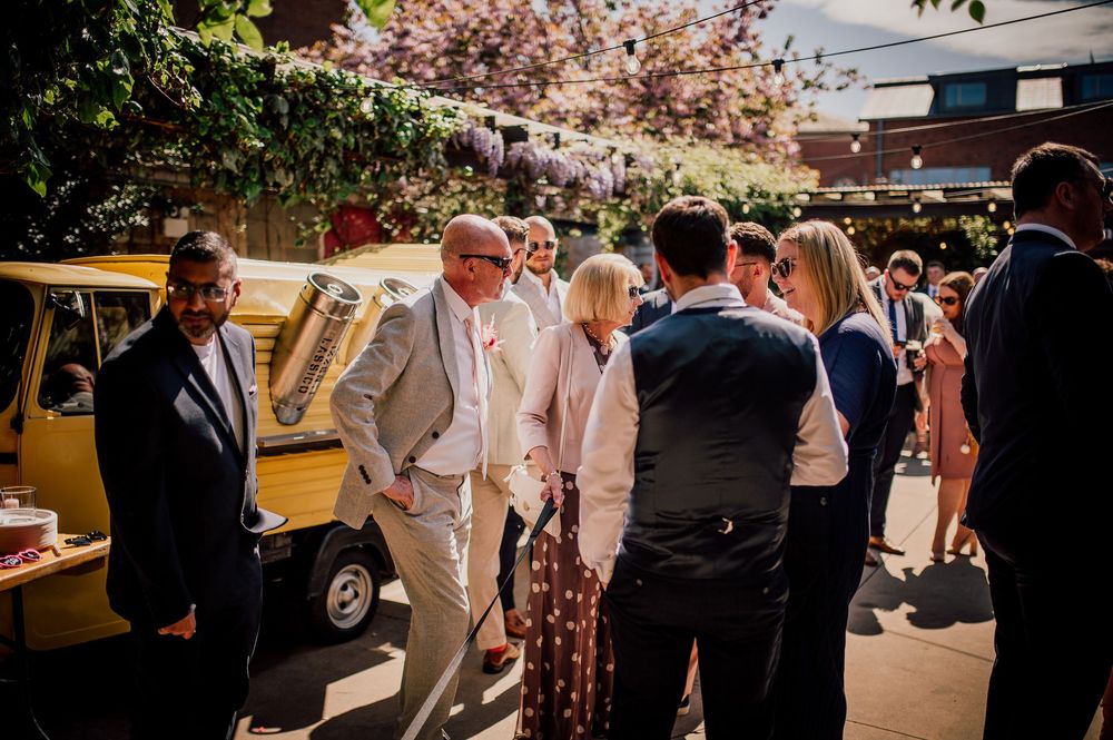 Wedding guests mingle and socialize during an outdoor reception gathering at a summer celebration.