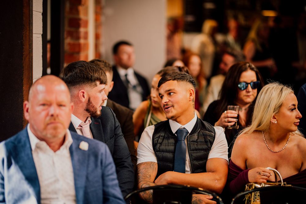 Wedding guests share laughter and joyful moments during an indoor reception celebration.