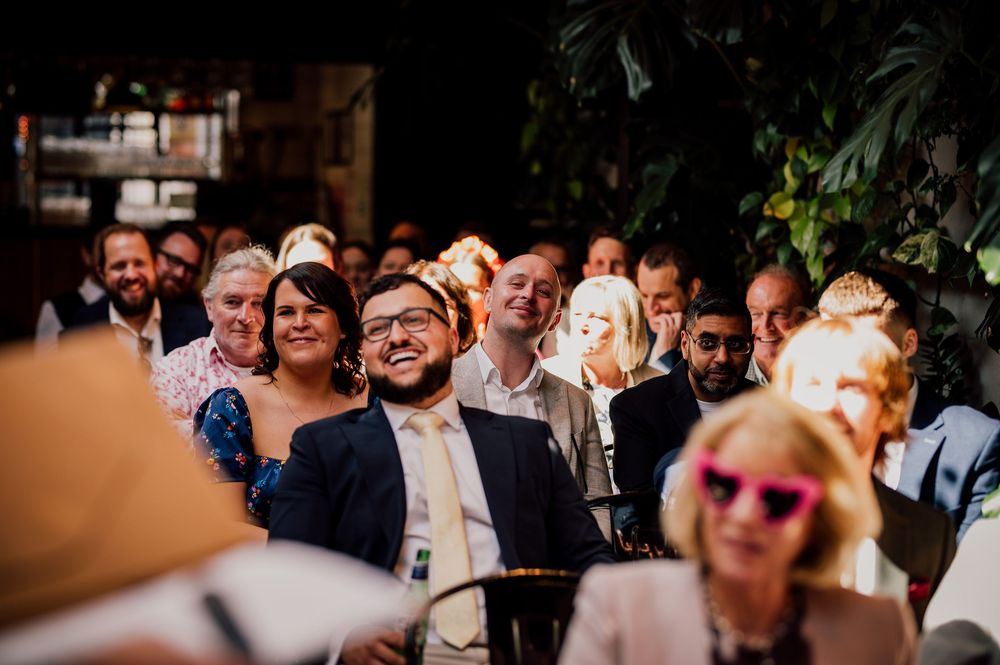 Wedding guests gather and socialize during an outdoor reception celebration at a rustic venue.