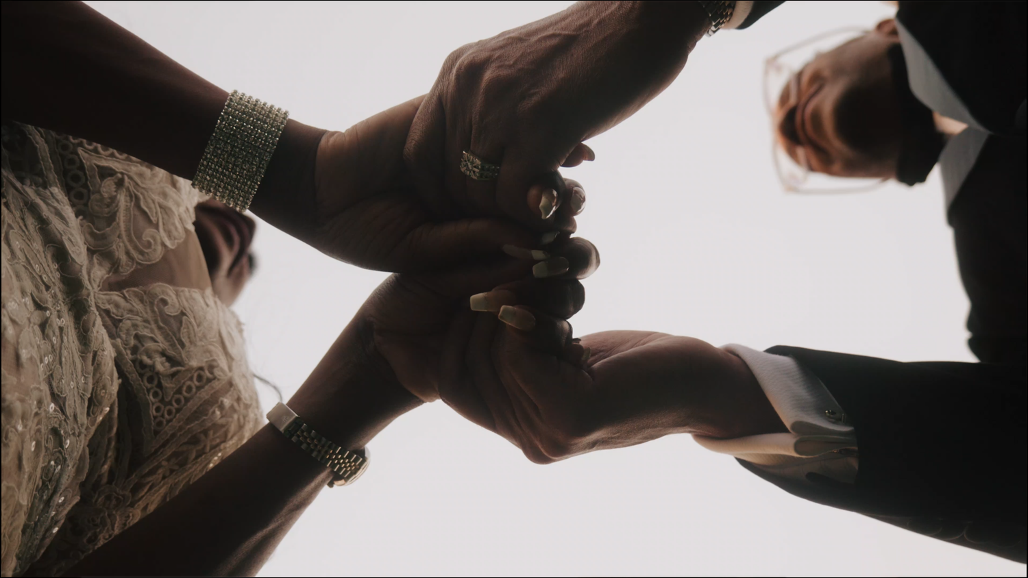 Two silhouetted hands form a heart shape against a bright background.