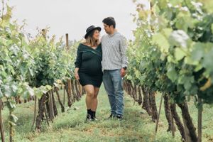 A couple shares an intimate moment while walking through a scenic vineyard.