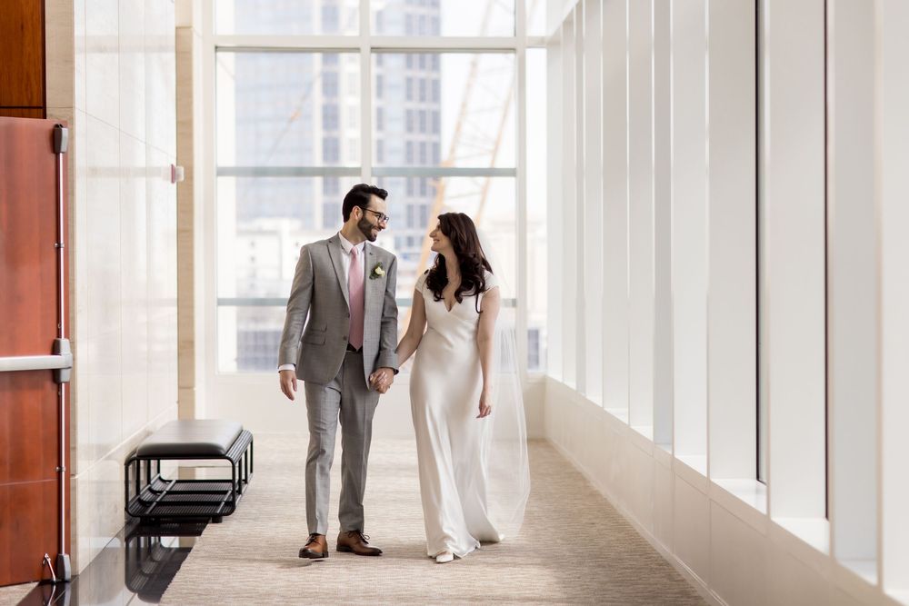 A couple walks down a bright hallway after their courthouse wedding ceremony.