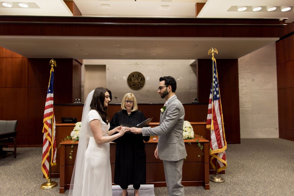 A couple in formal wedding attire stands in a courthouse setting during an intimate civil ceremony.