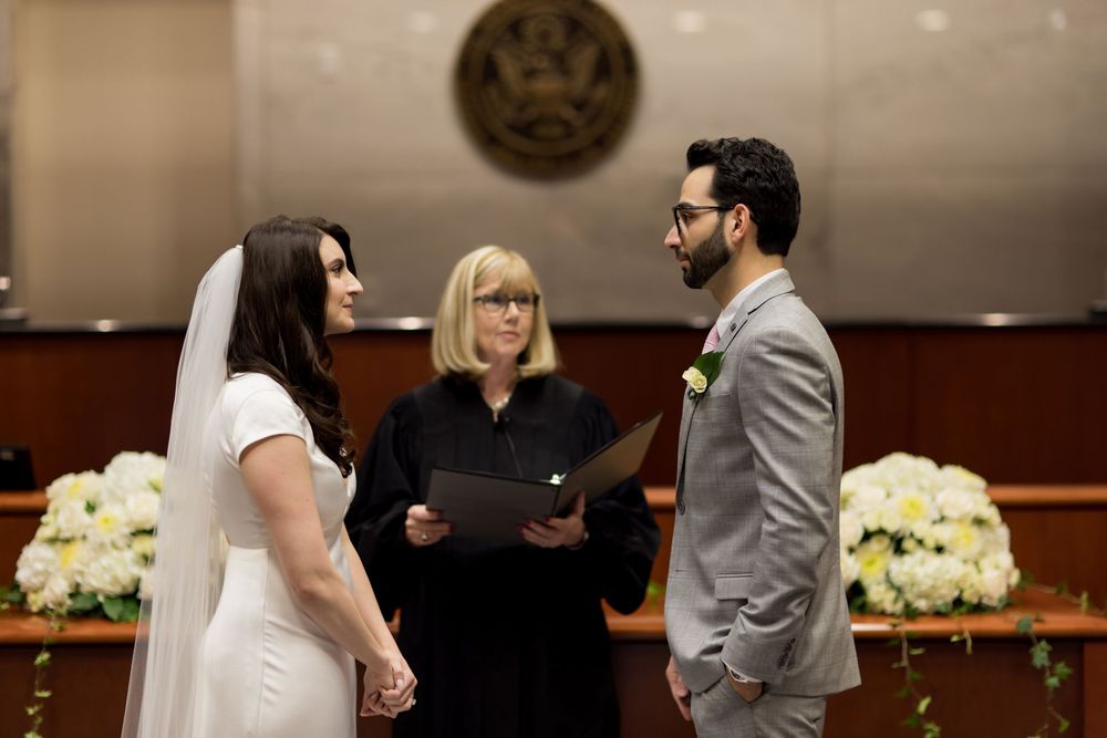 A wedding ceremony with guests seated in rows while a couple stands at the altar with an officiant.