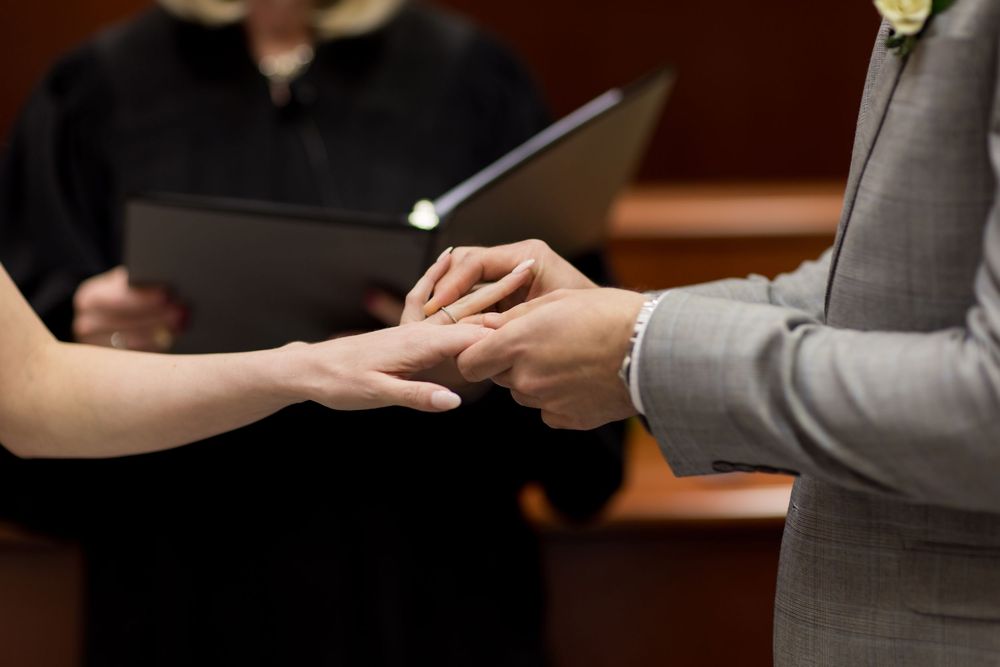 Two hands exchange papers during a formal business meeting at a wooden conference table.