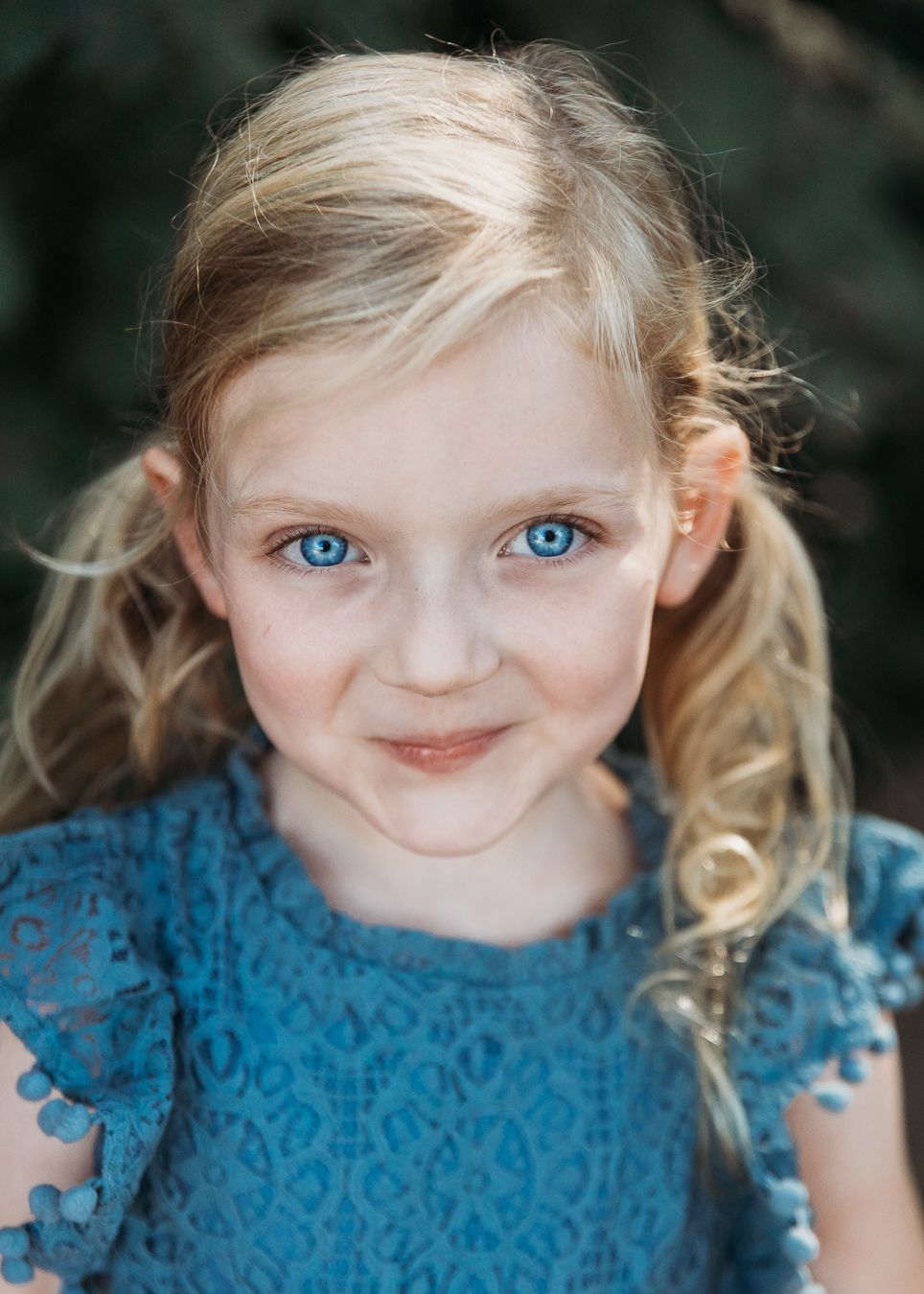 A series of close-up portraits showing a child in a blue lace top with blonde hair against a dark background.