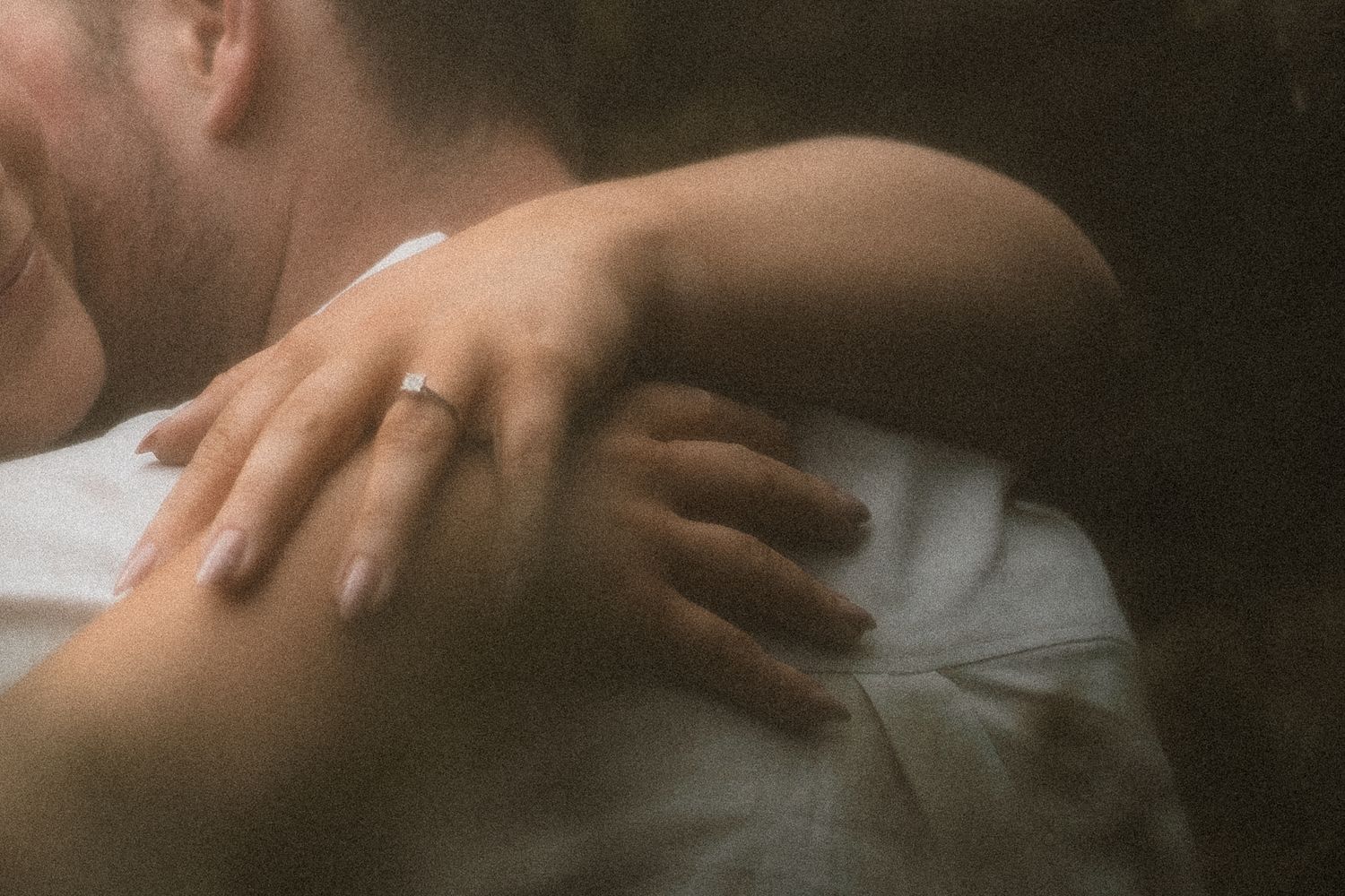 Close-up shot of hands embracing on white fabric in soft, intimate lighting in Marysville