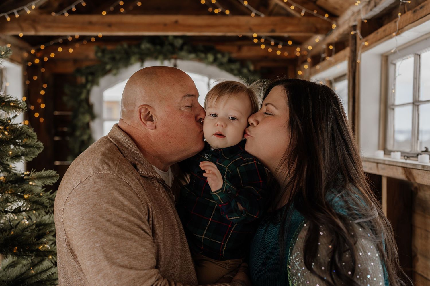 A family shares tender moments together in a rustic cabin setting with twinkling lights in the background.