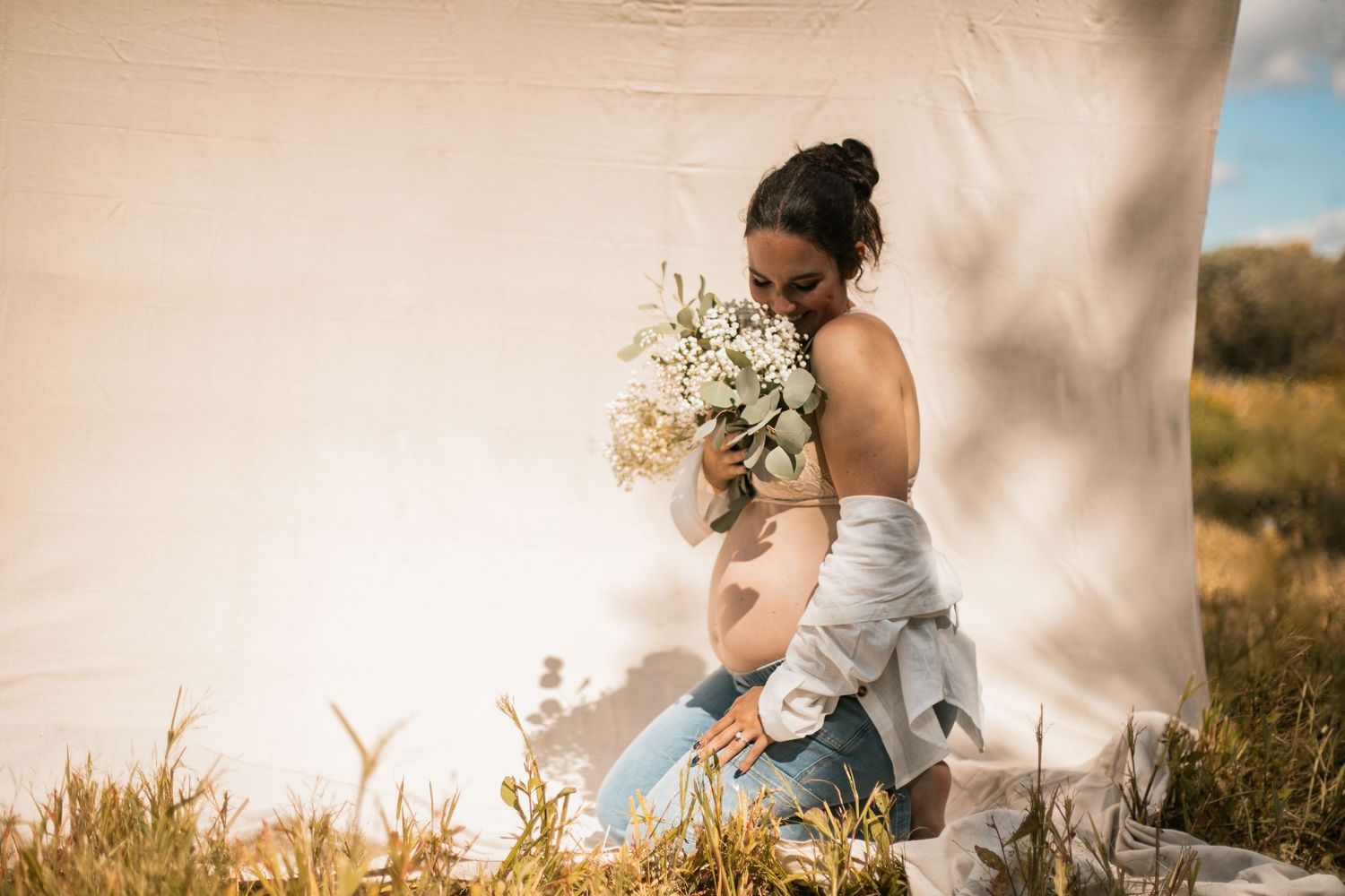 A romantic outdoor photo session with a white backdrop in a golden field during sunset.