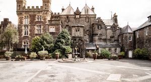 Panoramic view of a historic stone castle wedding venue with Gothic architecture and courtyard.