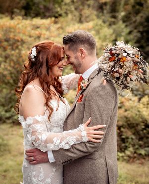 An intimate outdoor autumn wedding portrait with fall-colored florals and rustic attire.