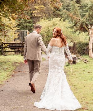 Newlyweds walking hand in hand along a garden path in autumn.