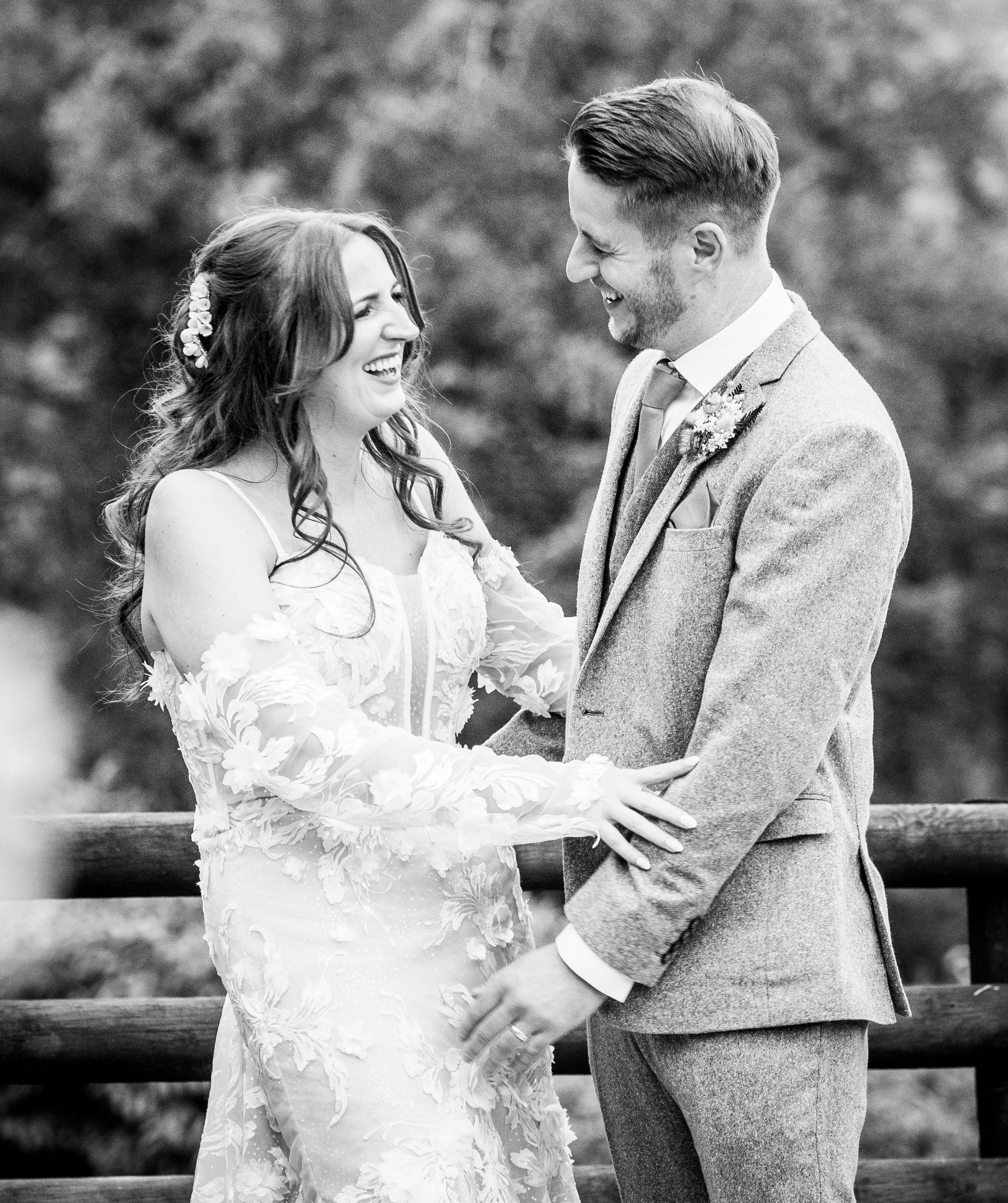 Black and white wedding portraits capture intimate moments between newlyweds on a rustic bridge.
