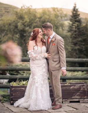Newlyweds share intimate moments on a stone bench overlooking scenic mountain views.
