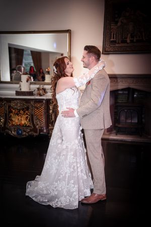 Couple dances together in an elegant indoor venue with dark wood details and ambient lighting.