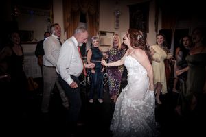 Wedding guests dancing and celebrating on a dark dance floor at the reception.