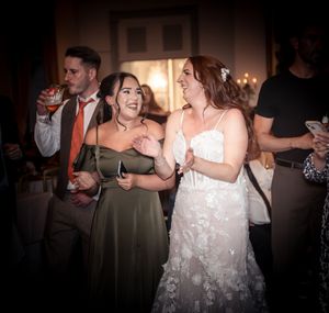 Wedding reception dance floor filled with guests celebrating in dimly lit venue.
