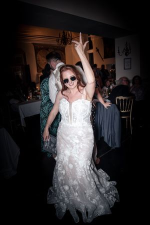 A bride dances joyfully at her wedding reception in a lace white gown.