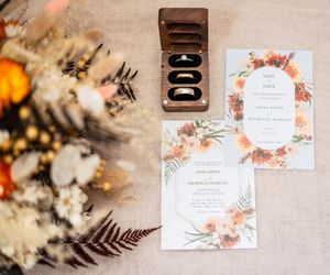 Wedding invitations with floral designs and text displayed against a neutral background with bokeh lighting effects.