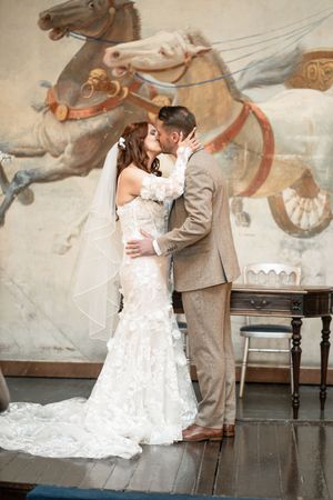 A couple shares an intimate first look moment in front of an ornate wall mural during their wedding day.