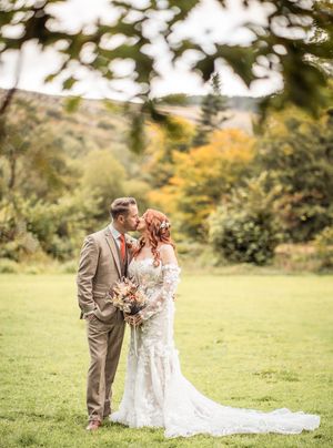 Couple in wedding attire share intimate moments in a scenic autumn field with golden foliage.