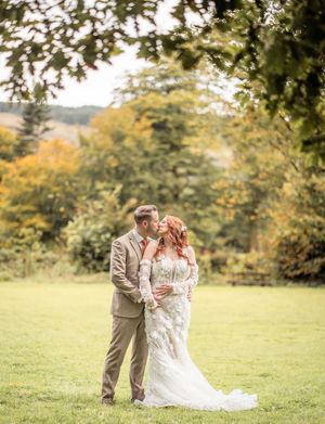 A couple embraces in a scenic outdoor field during golden hour.