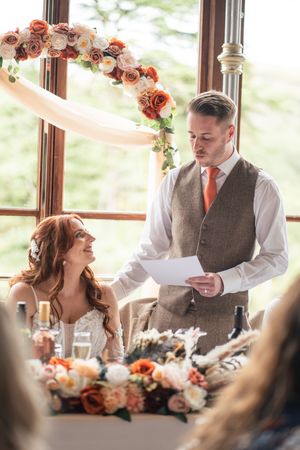Wedding reception scene with floral centerpieces and emotional moments during speeches.